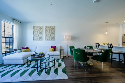 a living room and dining room with a white couch and a table with green chairs