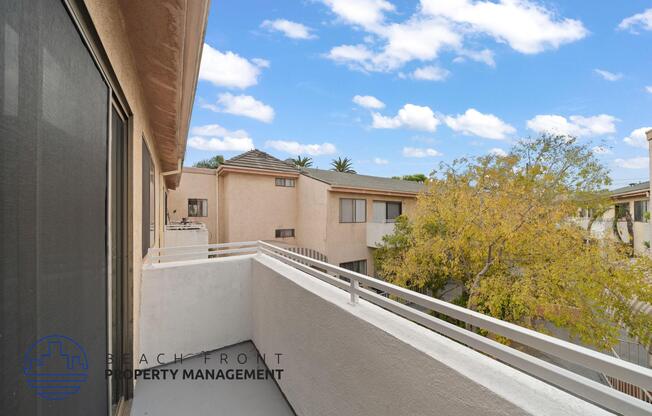 a balcony with a view of a building and a tree