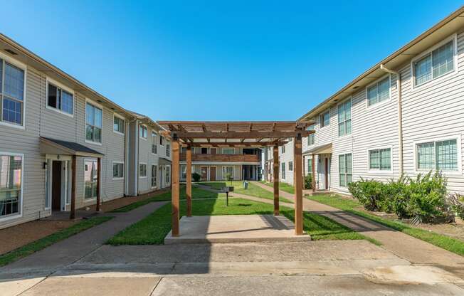 a pathway between two apartment buildings with a wooden canopy