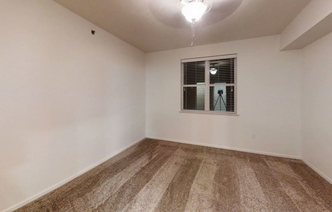 an empty living room with white walls and a window