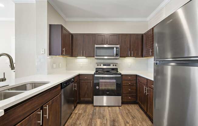 a kitchen with stainless steel appliances and wooden cabinets at The Verandah, Austin, TX, 78726