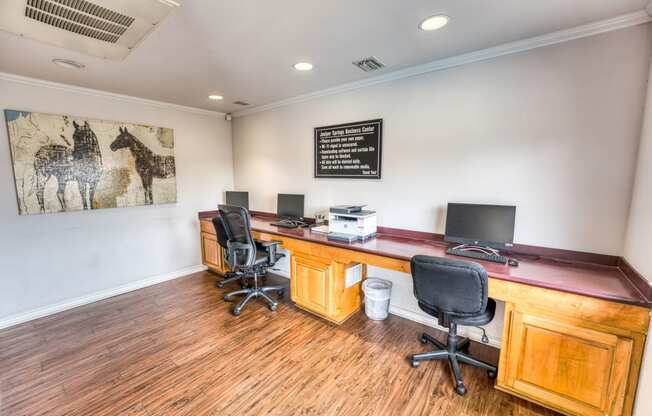 a room with two desks and two chairs and a painting on the wall