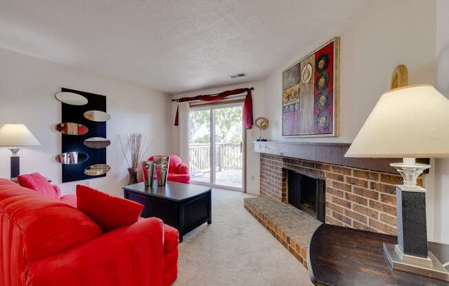 Living room in the one-bedroom model unit at Olde English Village, featuring a stone-brick fireplace and comfortable seating.