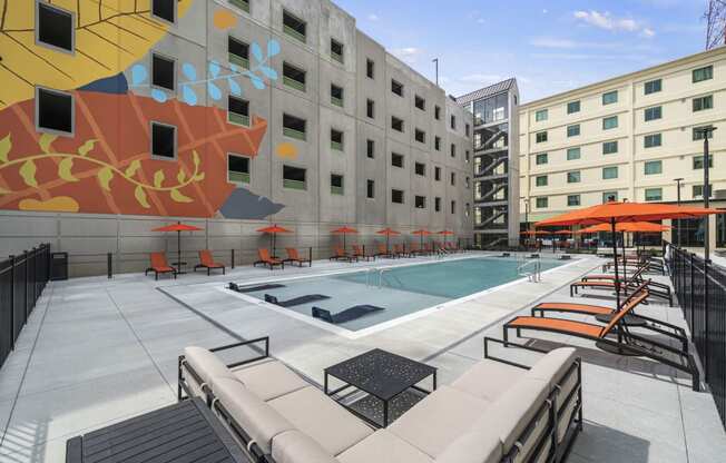 a pool with lounge chairs and umbrellas in front of a building  at The Icon, Richmond