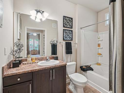 Modern apartment bathroom with granite-style countertops at Village at Broadstone Station in Apex, NC