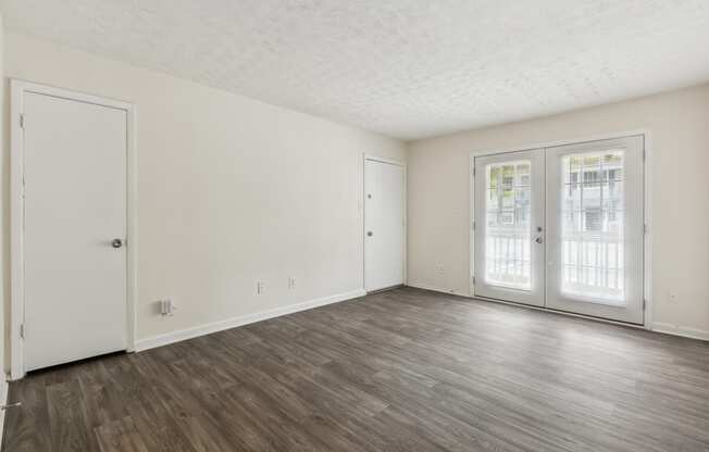 the living room of an apartment with white walls and wood floors