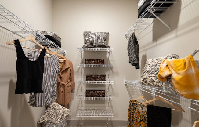 Model walk-in closet at our apartments in Atlanta, featuring clothes racks with baskets and clothes hanging.