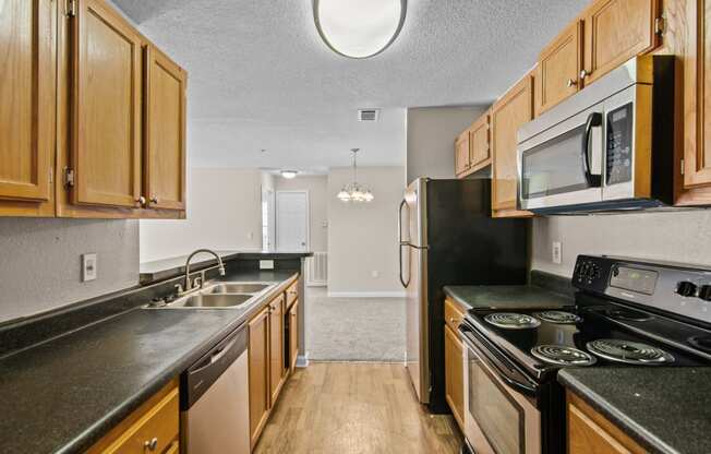 an empty kitchen with wood cabinets and black counter tops and appliances