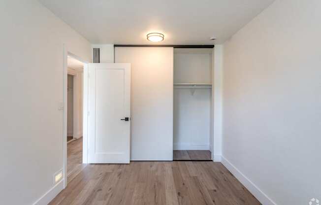 an empty room with white walls and wood floors and a closet