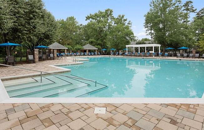 a large swimming pool with umbrellas and chairs around it at Trails at Short Pump Apartments, Virginia,23233