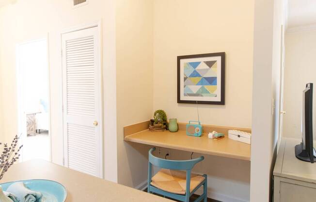 A blue chair sits in front of a desk with a plant on it.