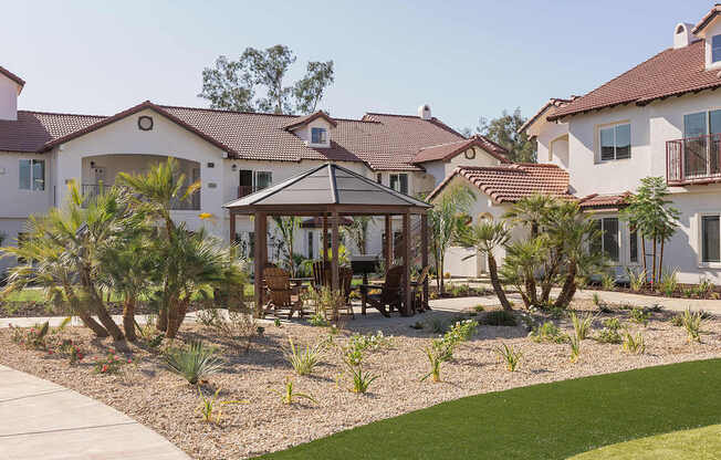 A house with a brown roof and a white wall with a garden in front.