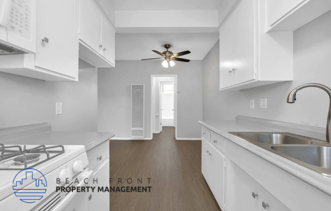 a kitchen with white cabinets and a sink and a ceiling fan