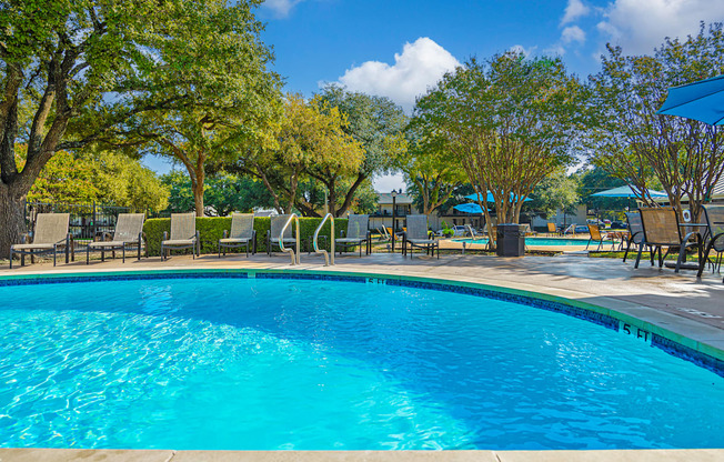 a swimming pool with chairs and umbrellas and trees