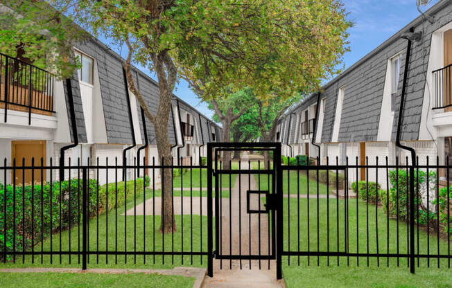 an open gate in front of a row of rental apartments