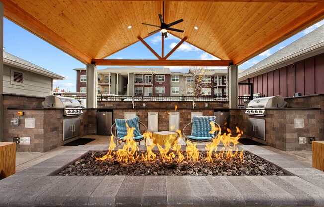 A patio with a fire pit and chairs.