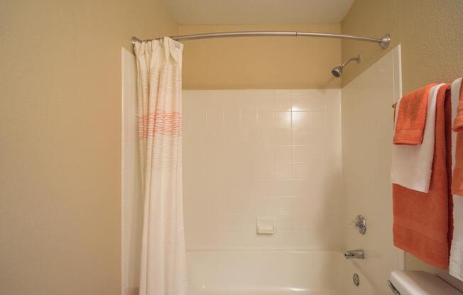 A bathroom with a white shower curtain and orange towels at Sterling Point Apartment Homes, Phoenix, AZ, 85042