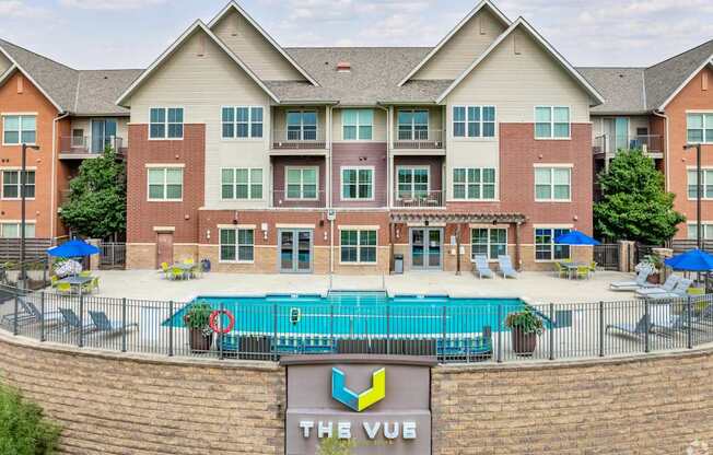 A large brick building with a pool in front and a sign that says "The Vue".