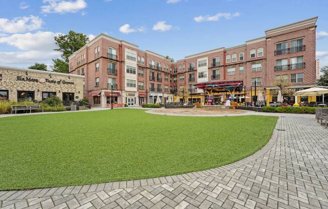A large grassy area in front of a building with a brick walkway.