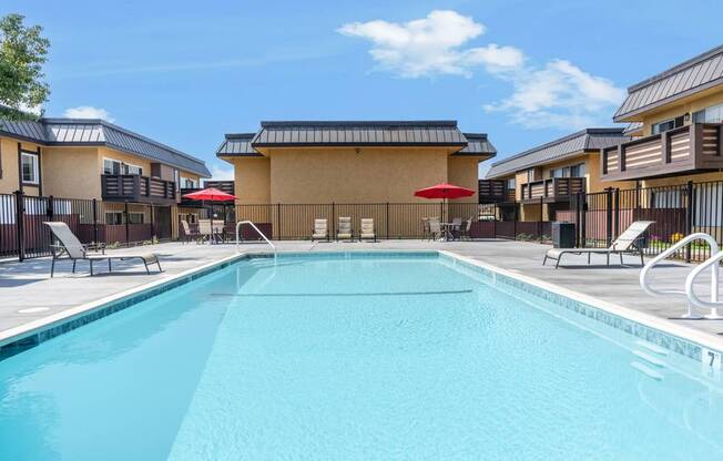 a swimming pool with chairs and umbrellas in front of a building