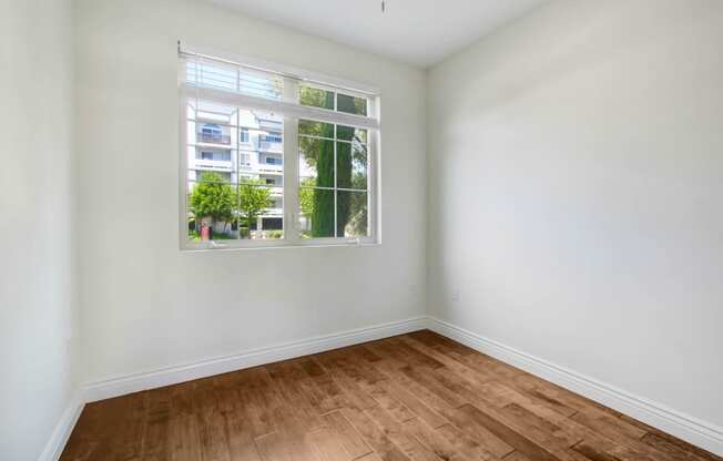 an empty room with a window and wooden floors