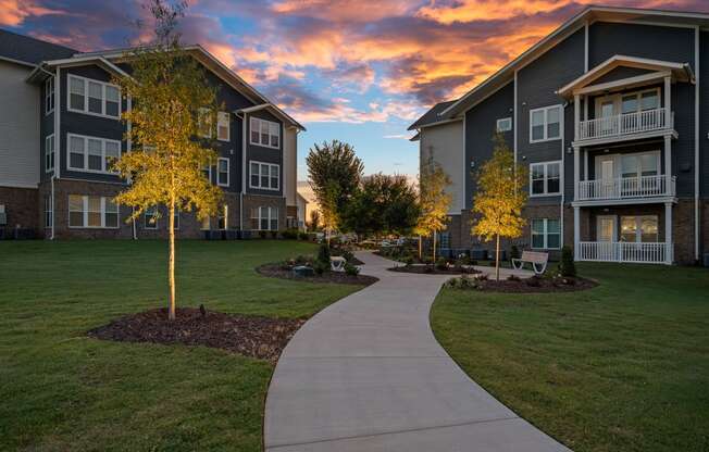 a sidewalk leading to an apartment building at sunset