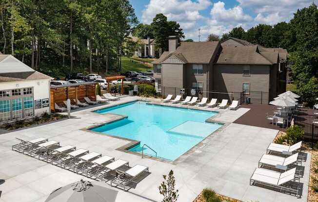 A large swimming pool surrounded by lounge chairs and umbrellas.