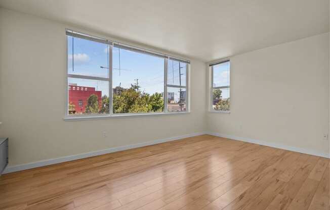 an empty living room with wood floors and large windows