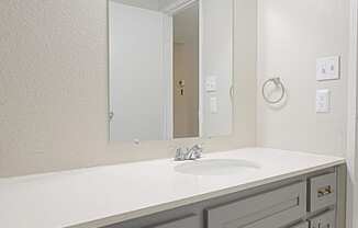 a bathroom with gray cabinets and white countertops