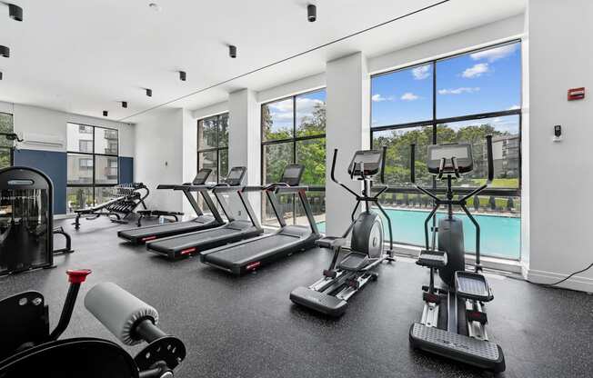A gym with treadmills, elliptical machines, and weights.