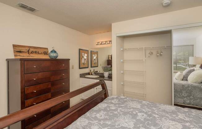 A bedroom with a bed, dresser, and a mirror at Bishop's Court Apartments, California, 95670