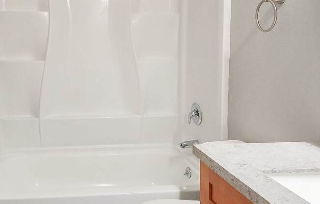 A white toilet sits next to a white bathtub in a bathroom.