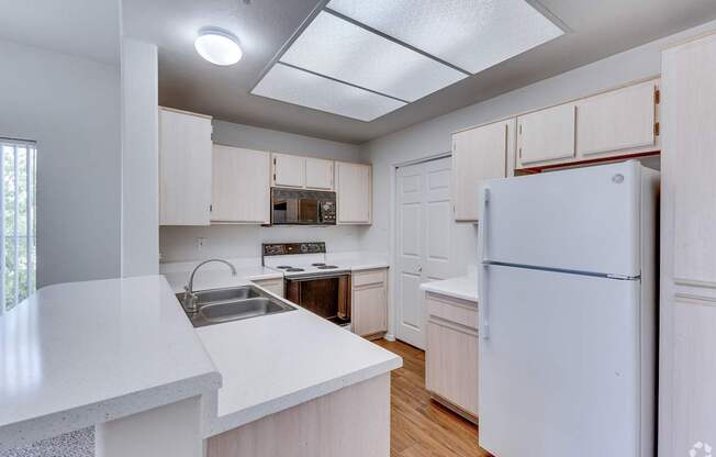 A white refrigerator is in the corner of a kitchen.