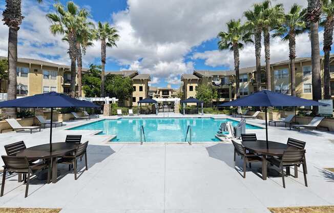 Pool area with tables and umbrellas at 55+ FountainGlen Temecula