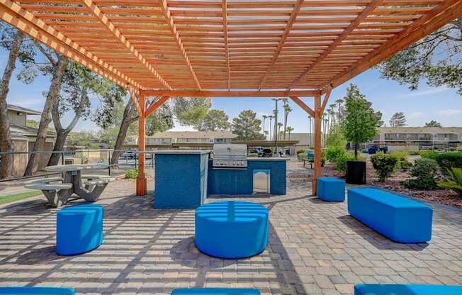 A wooden pergola with blue seating is in the foreground of the image.