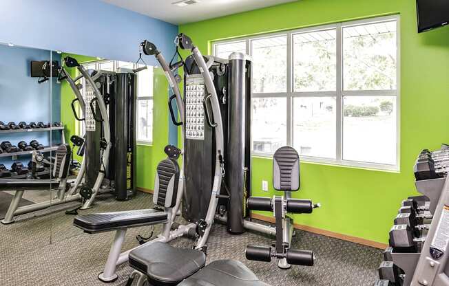 A gym with a variety of equipment including treadmills, weights, and exercise machines.