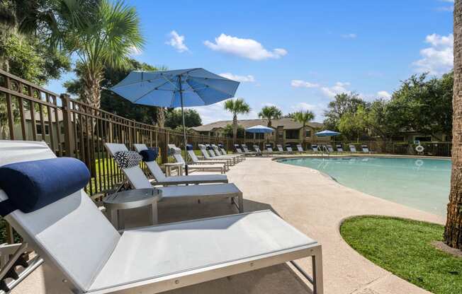 a pool with lounge chairs and umbrellas next to a pool