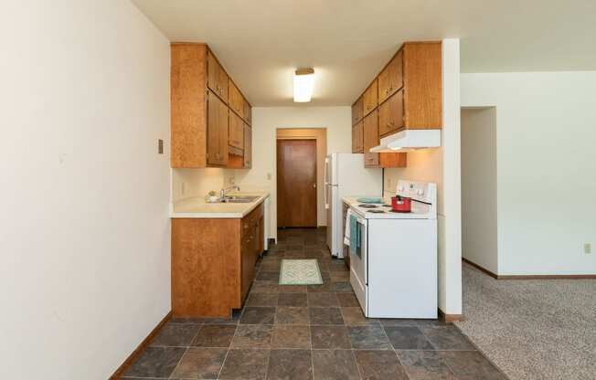 a kitchen with white appliances and wooden cabinets. Fargo, ND Islander Apartments