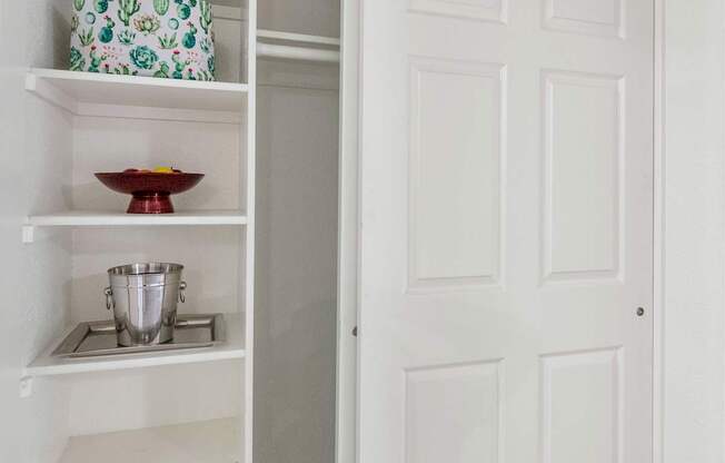 A white pantry with an open door and a bowl on the shelf at Urban WalkApartments on 6th Avenue, Phoenix, AZ