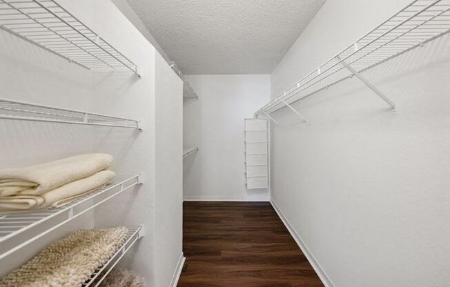 a walk in closet with white closets and white walls