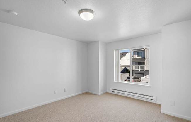 a bedroom with a large window and white walls