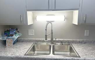 a stainless steel sink in a kitchen with white cabinets