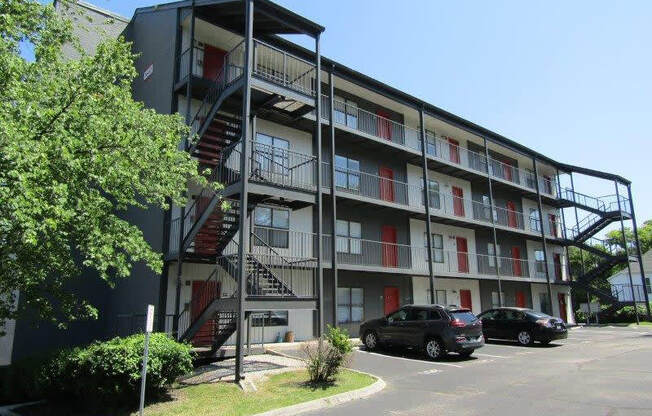 a building with a fire escape and two cars parked in front of it