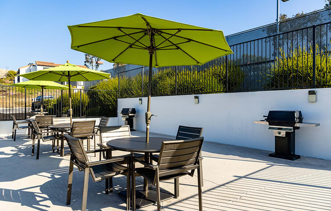 A patio with a table and chairs and a grill.