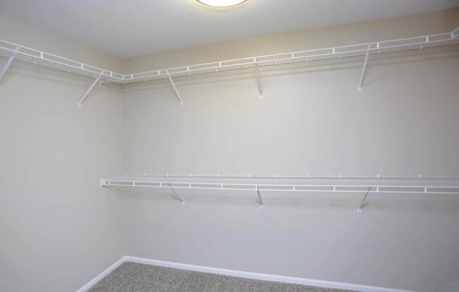 Inside of spacious walk in closet with plenty of shelves and hanging space.