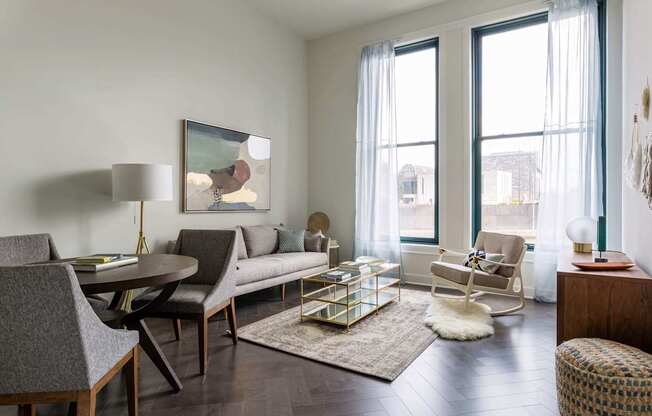A living room with a grey couch, a coffee table, and a painting on the wall at The Pennsylvanian Apartments, Pittsburgh, PA, 15222