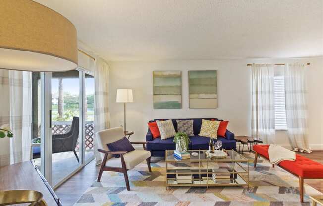 Living room with patterned area rug and colorful couch, chair, and ottoman with coffee table