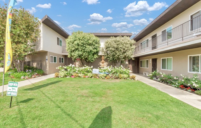 a yard in front of a building with grass and flowers