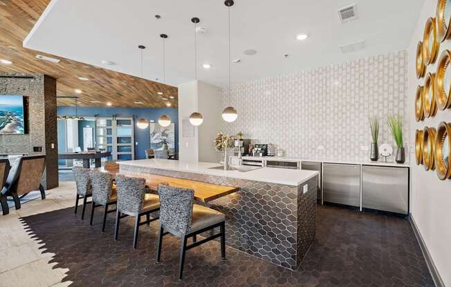 A modern kitchen with a wooden island and grey chairs.