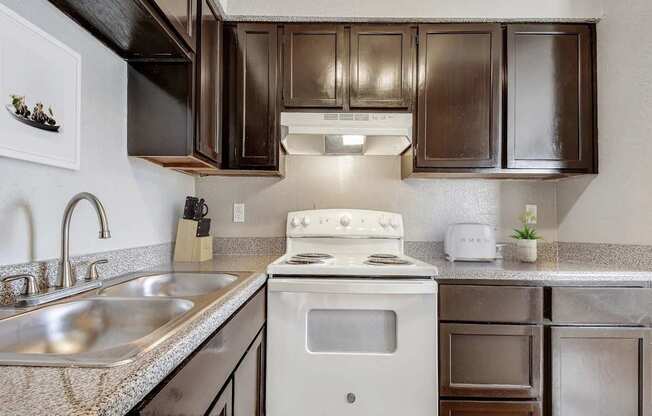 A kitchen with a white stove and brown cabinets.